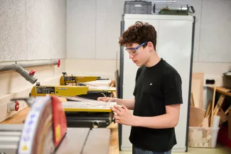Leerling op het Kamerlingh Onnes zaagt met een figuurzaag.